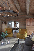 Chandelier and yellow armchairs in living room of log cabin