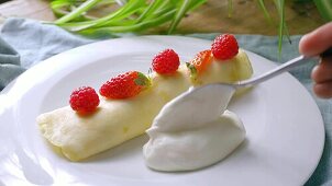 Stuffed crepes with cream, strawberries and raspberries being made