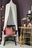 Chair under canopy in child's bedroom with purple walls