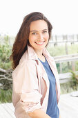 A young brunette woman wearing a blue t-shirt with a pale pink shirt blouse