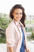 A young brunette woman wearing a blue t-shirt with a pale pink shirt blouse