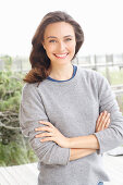 A young brunette woman wearing a grey woollen jumper with an under shirt