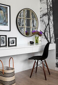 Runder Spiegel mit Sprossen überm Schreibtisch mit schwarzem Stuhl