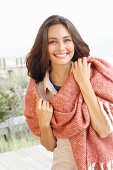 A young brunette woman wearing a light shirt blouse with a salmon pink woollen shawl