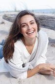 A young brunette woman wearing wearing a white tunic with a woollen jumper over her shoulders