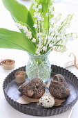 Posy of lily-of-the-valley and bird ornaments in flan tin