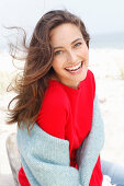 A young brunette woman wearing a red jumper with a grey woollen shawl