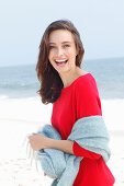 A young brunette woman wearing a red jumper with a grey woollen shawl