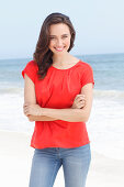 A young brunette woman wearing a red blouse and jeans