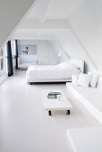 Minimalist, white bedroom below sloping ceiling