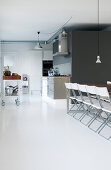 Row of folding chairs on white floor in front of open-plan kitchen