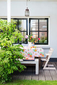 Blümchentischdecke und Blumenstrauß auf dem Tisch auf der Terrasse