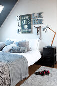 Motto and decorative letters on wall above double bed with scatter cushions