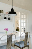 Metal chairs at the dining table with black industrial ceiling light