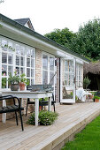 Terrasse mit Holzboden vorm Wintergarten mit Sprossenfenstern