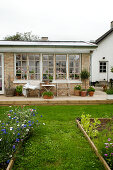 Raised garden beds in front of the brick house with terrace