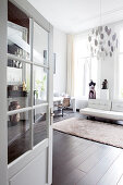 Blick durch geöffnete Tür auf weiße Ledercouch und Schneiderpuppe in Loft-Wohnung