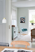 View over dining table into living area with rocking chair and muted colour scheme