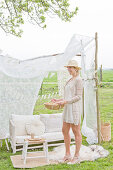 Sofa in the DIY garden pavilion made of branches and a white curtain