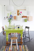 Green-painted dining table and various chairs in dining area