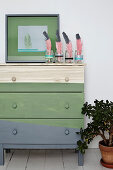 Green and gray painted wooden chest of drawers with feathers as decoration