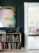 Bookshelf on a black wall, view into the living room in pastel colors