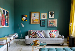 Picture gallery above the sofa in the living room with petrol blue walls