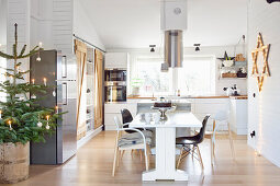 Kitchen in white with kitchen island and dining table that is decorated for Christmas