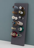 Gray board as a holder for spools of thread and fabric ribbons