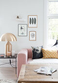 Pink upholstered suite, golden table lamp, and rustic coffee table in the living room