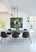 Dining table with black classic chairs, pendant light above in open living area