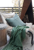 Stuhl mit Kissen, Tierfell und Plaid auf der Terrasse
