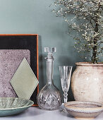 Crystal carafe and glass, ceramic planter with a little tree and bowls on a shelf