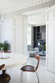 Round table with classic chairs in the dining area view through open double doors into the living room