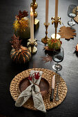 A place setting and candles on autumnally decorated table
