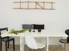 Holzleiter als Deko an der Wand überm Esstisch mit schwarzen und weißen Stühlen