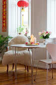 Rosen auf dem Tisch mit verschiedenen Stühlen unterm Asia-Lampion