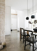 Old wooden chairs at a dining table in an open-plan living room with a concrete floor