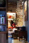 A view of an armchair with ethnic upholstery in front of a brick wall in the corner of a room