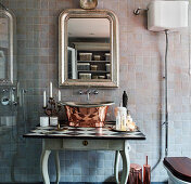 Metal sink on a wooden table under an antique mirror in the bathroom