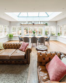 Chesterfield sofa and dining table below skylight in open-plan interior