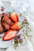 Gestürzter Schokoladenpudding dekoriert mit Erdbeeren und Erdbeerpulver