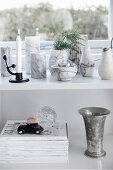 Marble vases on shelf below window and above stacked magazines and silver goblet