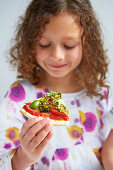 Mädchen isst ein Stück Gemüsepizza