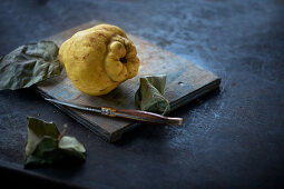 A quince on a wooden board with a knife