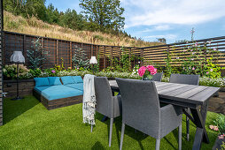 Garden table and loungers in garden with raised beds and screen fences