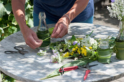 Wiesenblumen in hübsch verkleideten Flaschen