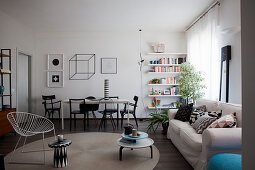 Scatter cushions on sofa, side table and armchair in front of dining area and book shelves
