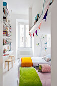 Light-flooded children's sleeping area with beds and tall shelving above desk