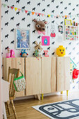Sideboard aus Holz im Kinderzimmer mit Pferde-Tapete und bunter Deko